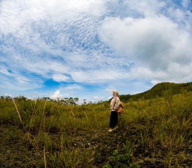 Beautiful Asian in meadow with kelud mountain and blue sky background