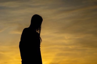 Gün batımında Asyalı bir kadının silueti. Yalnız bir kadının yansıması, içine kapanık bir kadın. Dünya Dönüşüm Günü.