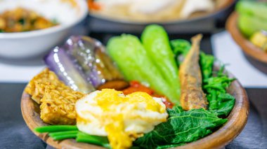 Kızarmış patlıcan, kızarmış tempeh, kızarmış tuzlu balık ve chayote ile bir toprak kapta Endonezya baharatı (sambal).