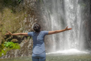 Neşeli Asyalı kadın şelaleye tek başına gidiyor. Şelalenin güzelliğinin ve serinliğinin tadını çıkar..