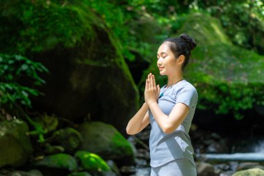 Doğada yoga yapan Asyalı bir kadın. Doğada huzur aramak..