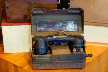 Masanın üzerinde eski kahverengi ve siyah bir telefon var. Eski bir iletişim cihazı..