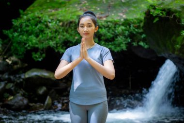 Doğada yoga yapan Asyalı bir kadın. Sağlıklı bir bedeni ve zihni korumak..