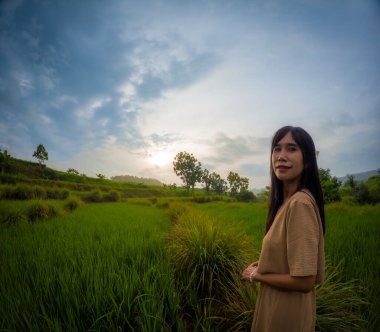Asyalı kadın köyde tek başına seyahat ediyor. Yeşil pirinç tarlalarının tadını çıkarıyorum..