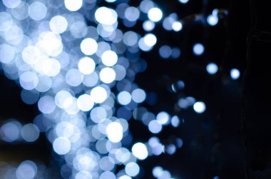 Odak arkaplanından bulanık Noel ışıkları. Bokeh karanlık bir arkaplanda parlıyor. Noel için dekorasyon ve grafik tasarım için Noel dokusu..
