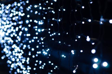 Odak arkaplanından bulanık Noel ışıkları. Bokeh karanlık bir arkaplanda parlıyor. Noel için dekorasyon ve grafik tasarım için Noel dokusu..