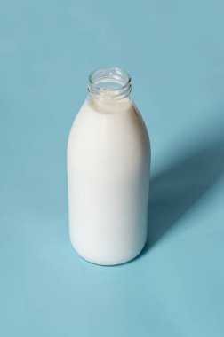 Süt şişesi mavi arka planda pop sanat tarzında. Minimalizm, dikey yönelim.