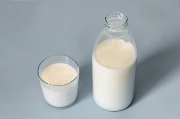 Butelkę mleka lub kefiru i szklankę w pobliżu na szarym tle. Zdrowy, pożywny, smaczny produkt. Przestrzeń do kopiowania z bliska. — Zdjęcie stockowe