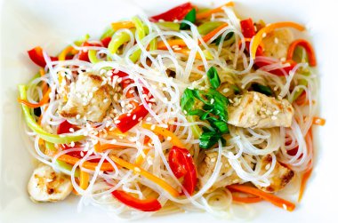 Cam erişteli Asya salatası, et ve sebze - havuç, dolmalık biber ve beyaz tabakta susam tohumu. Düz yat, yakın plan. Yatay yönelim.