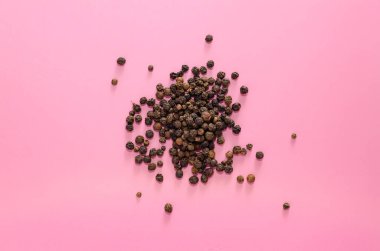 Pembe arka planda kurumuş karabiber serpiştirilmiş. Baharatlı, sağlıklı bir baharat. Boşluğu kopyala, sert gölgeler, pop sanatı.