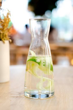 Cam bir şişede limonlu ve salatalıklı su. Tahta bir masada arınma ya da diyet için Sassy suyu. Sağlıklı yiyecekler, kilo kaybı, yaşam tarzı konsepti. Yakın plan. Yan görünüm, dikey yönelim.