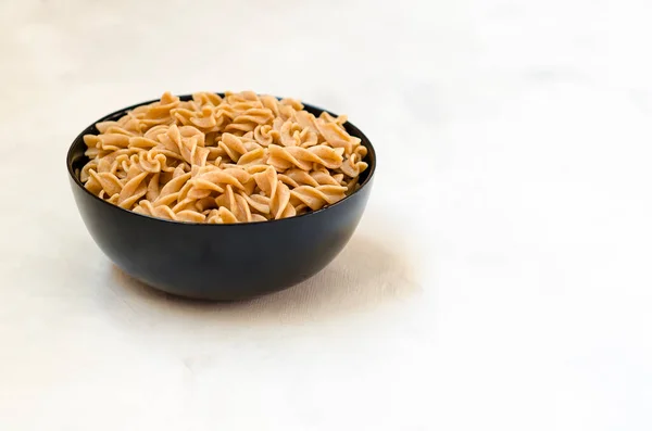 Organic buckwheat Fusilli pasta in a black bowl. Gluten Free Whole Grain Noodles. Healthy food concept. Side view. Copy space. — ストック写真