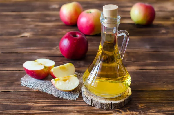 Apple vinegar in a glass bottle. Fermented Fruit Cider Organic Apples Wooden Background Side View Healthy Eating and Lifestyle Concept.