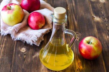 Elma şarabı sirkesi, ahşap bir masada cam bir şişede. Mayalanmış elma suyunun sonucu olan Malic asit, sağlık için çok yararlıdır ve yemek pişirmek için kullanılır..