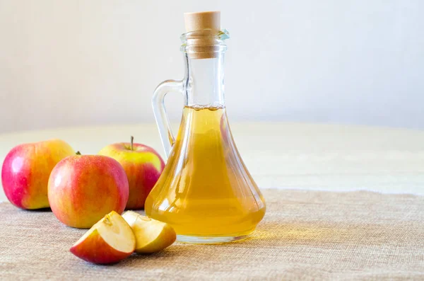 Cuka sari apel dalam botol kaca dengan latar belakang cahaya dengan apel merah. Asam malat bermanfaat bagi kesehatan dan digunakan untuk memasak. Orientasi horisontal. — Stok Foto