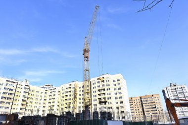 Mavi gökyüzüne karşı vinç ve inşaat alanı