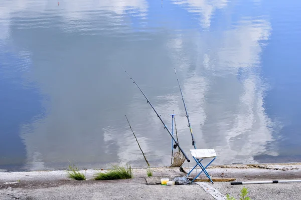 Cadeira com postes de pesca e equipamento de pesca no lago — Fotografia de Stock