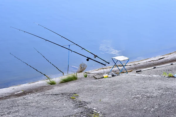 Καρέκλα με πόλους αλιείας και αλιευτικό εξοπλισμό στη λίμνη — Φωτογραφία Αρχείου