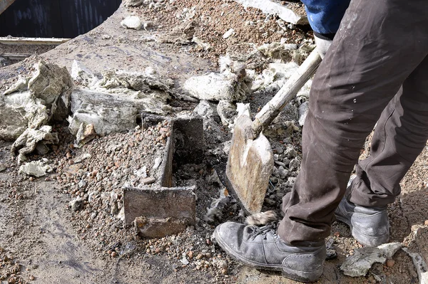 Trabajador desconocido con una pala limpiando escombros de construcción — Foto de Stock
