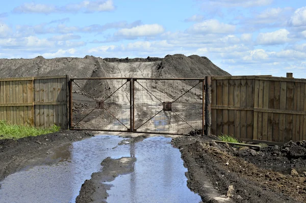Dirt road, a pool and a lot of stored in the open air ground for a closed fence — Stock Photo, Image