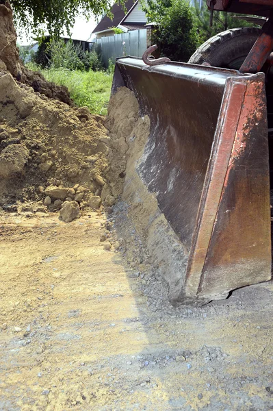 Cubo de excavadora cavando una zanja en el suelo de tierra — Foto de Stock