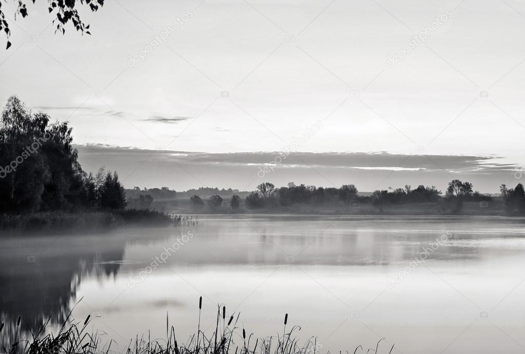 The morning landscape with sunrise over water in the fog. Black