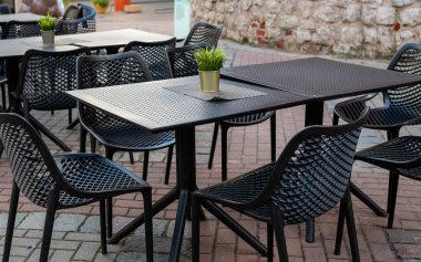 Açık kahve masaları ve şehir caddesi boyunca dizilmiş siyah renkli sandalyeler, şık şehir kahve terası manzarası..