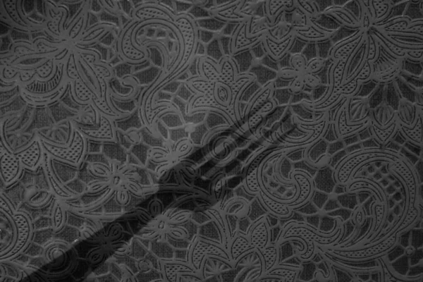 Dekoratif çiçek desenli siyah-beyaz duvar desenli ve yüzeyine yumuşak bir gölge düşüyor. Klasik süsleme detaylarıyla sanatsal soyut arkaplan.