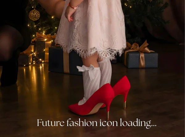 A charming Christmas scene featuring a toddler wearing oversized red high heels in front of a glowing Christmas tree and gifts. Playful holiday fashion concept highlighting childhood imagination and festive elegance.