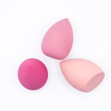 Beyaz arka planda üç farklı şekildeki pembe makyaj süngeri. Makyaj uygulaması, cilt rutini, güzellik ürünleri ve kişisel bakım ile ilgili kozmetik güzellik aletleri konsepti. Kopya alanı ile en az temiz bileşim.