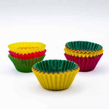 Beyaz arka planda izole edilmiş renkli kağıtlı kek kalıpları. Kekler, kekler, ev yapımı tatlılar, parti hazırlıkları ve yemek tasarımı ile ilgili yemek malzemeleri konsepti. Kopyalama alanı ile en az bileşimi temizle.