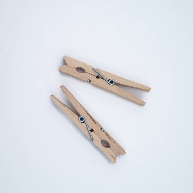 Minimalist düz bir zemin üzerine yerleştirilmiş iki tahta mandalın görüntüsü. Kompozisyonda basitlik, günlük nesneler, denge ve işlevsellik vurgulanıyor.