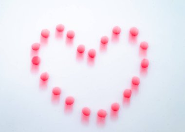 Beyaz arkaplandaki küçük pembe noktalardan oluşan, kasıtlı hareket bulanıklığı ve uzun pozlama kullanılarak yaratılmış bir kalp şeklinin soyut stüdyo görüntüsü. Yumuşak odak ve kamera hareketi, aşkla ilgili kavramlar için uygun rüya gibi, sanatsal bir etki yaratıyor..