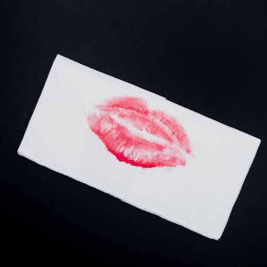 Siyah arka plana yerleştirilmiş beyaz kağıt mendildeki kırmızı ruj izi minimalist kavramsal görüntüsü. Kompozisyon samimiyet, arzu, şefkat, kadınlık ve duygusal ifade taşır..