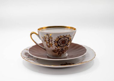 Altın desenli çay tabağı desenli, beyaz arka planda izole edilmiş klasik porselen çay fincanı. Çay ya da kahve için klasik sofra takımı. Stüdyo çekimi.