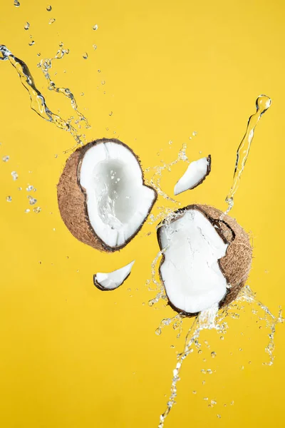 Floating coconut breaking with coconut water splash, On yellow background.