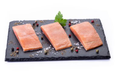 Üç çiğ somon fileto, beyaz arka planda siyah tahta üzerine..