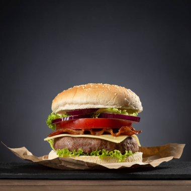 Koyu arkaplanda ahşap tabanda hamburger.