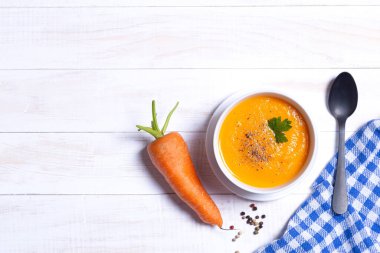 Havuç çorbası kasesi ve beyaz ahşap masa. Üst Manzara. Kopyalama alanı ile.