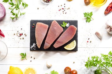 Beyaz arka planda siyah tabakta taze çiğ ton balığı bifteği. Üst görünüm.