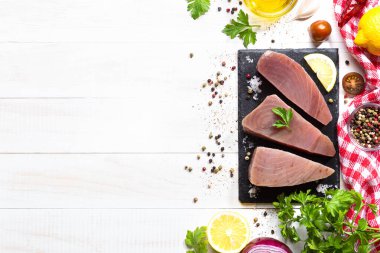 Beyaz arka planda siyah tabakta taze çiğ ton balığı bifteği. Kopyalama alanı olan üst görünüm.