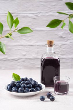 Beyaz zemin üzerinde yabanmersini suyu olan sürahi ve bardak..