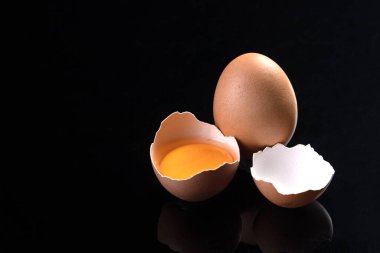 Yumurta ve kırık tavuk yumurtası siyah arkaplanda izole edilmiş..