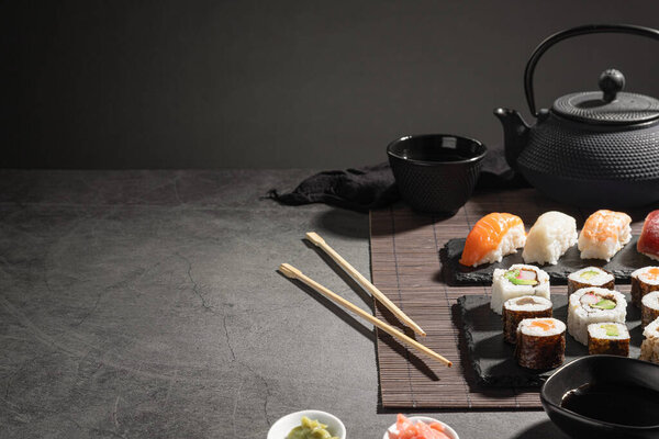 Variety of Fresh sushi  and japanese tea on dark background with copyspace.