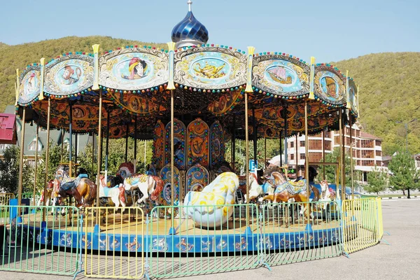 Carousel, a childrens attraction in Sochi, Russia. View of mountain peaks — Stock Photo, Image