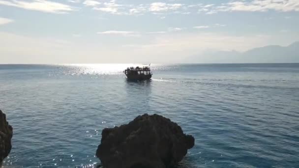 岩の多い海岸から海と山への眺め 小さなボートが岸から離れて移動している 夏の美しい海 — ストック動画