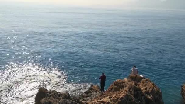Fischer Felsigen Ufer Angeln Zwei Männer Vor Dem Hintergrund Schimmernder — Stockvideo