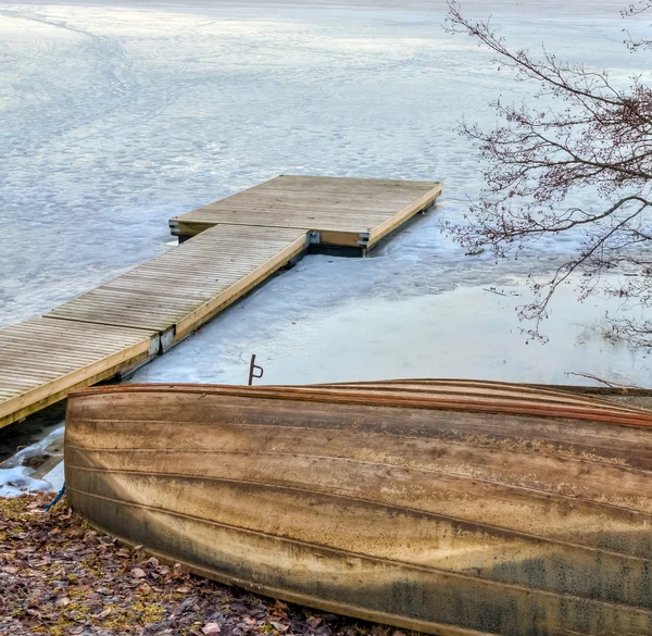 Oude houten roeiboot en pier in de bevroren meer — Stockfoto