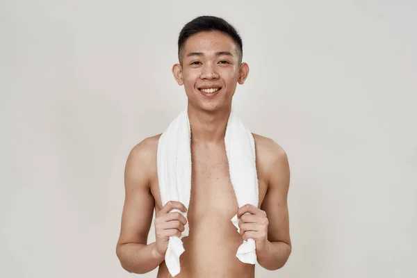 Portrét mladého asijského muže bez košile s problematickou pletí a hyperpigmentací na obličeji pózující s ručníkem kolem krku izolovaným přes bílé pozadí — Stock fotografie