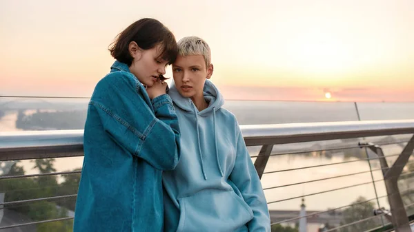 Young loving lesbian couple enjoying romantic moments together while standing on the bridge at sunrise — Stock Photo, Image